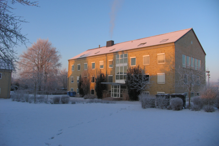 Gebäude mit gelben Klinkern im Winter, Schnee im Vordergrund